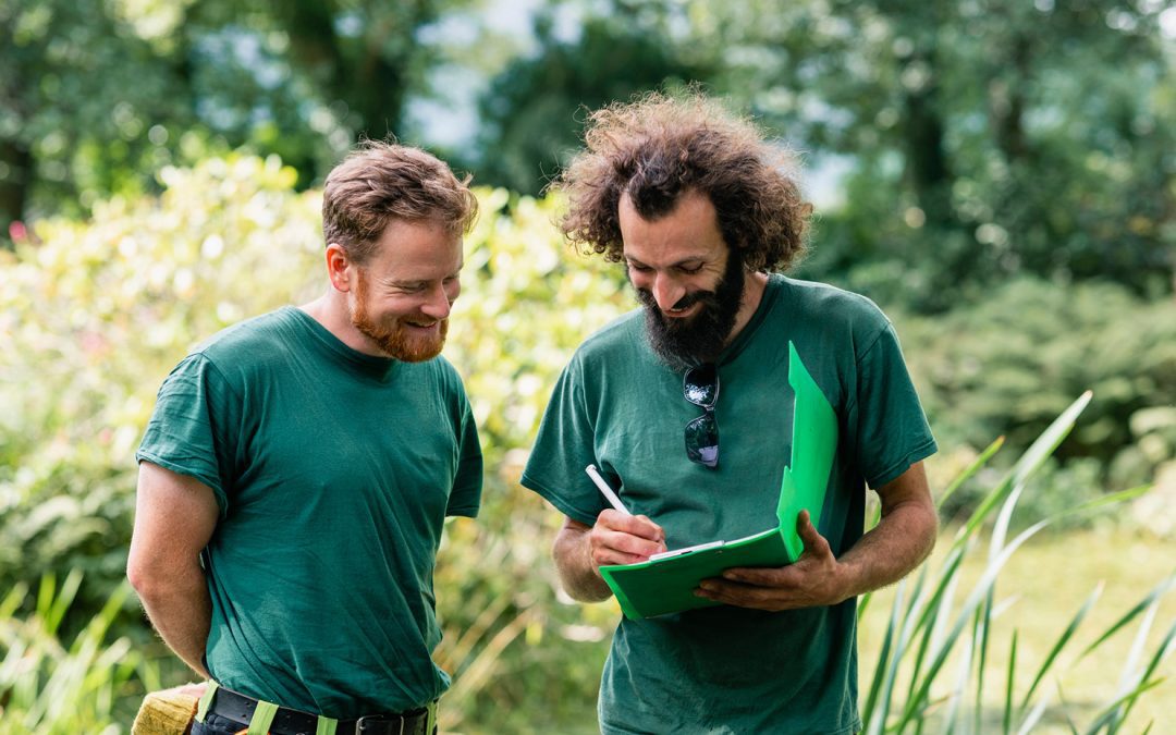 Two men planning ground work on estate, writing ideas and smiling