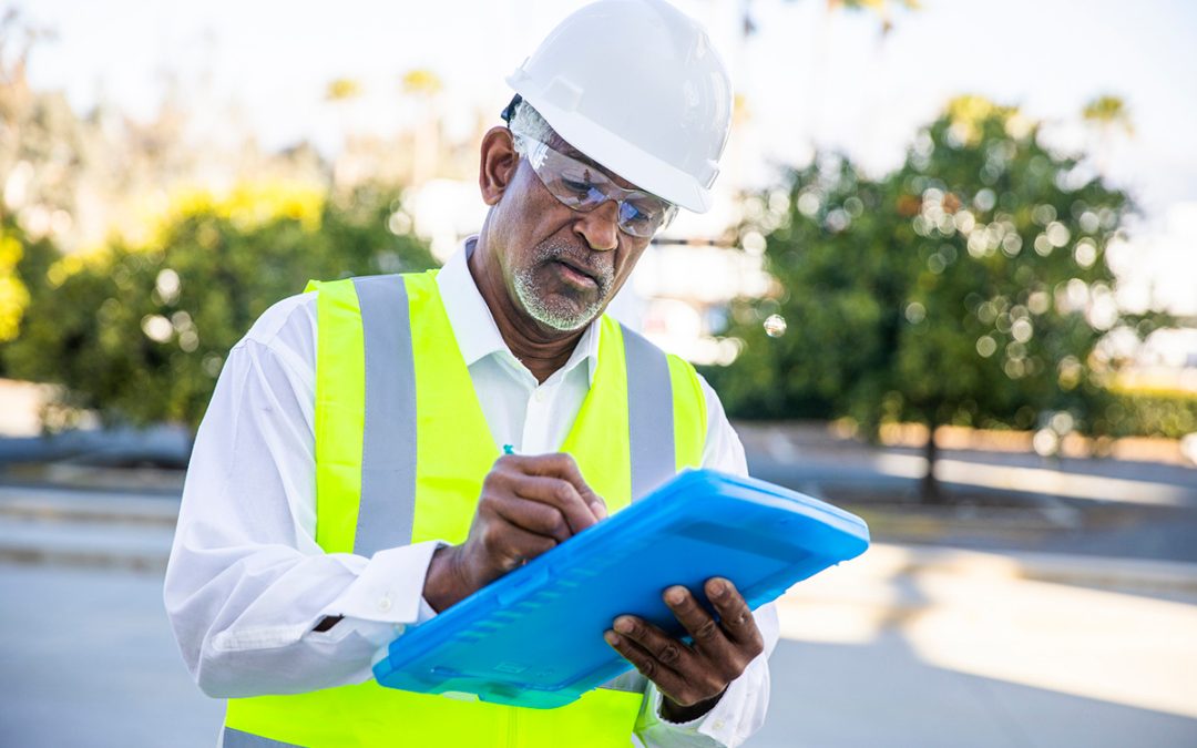 A senior black male landscaping site manager visually inspects a landscaping project